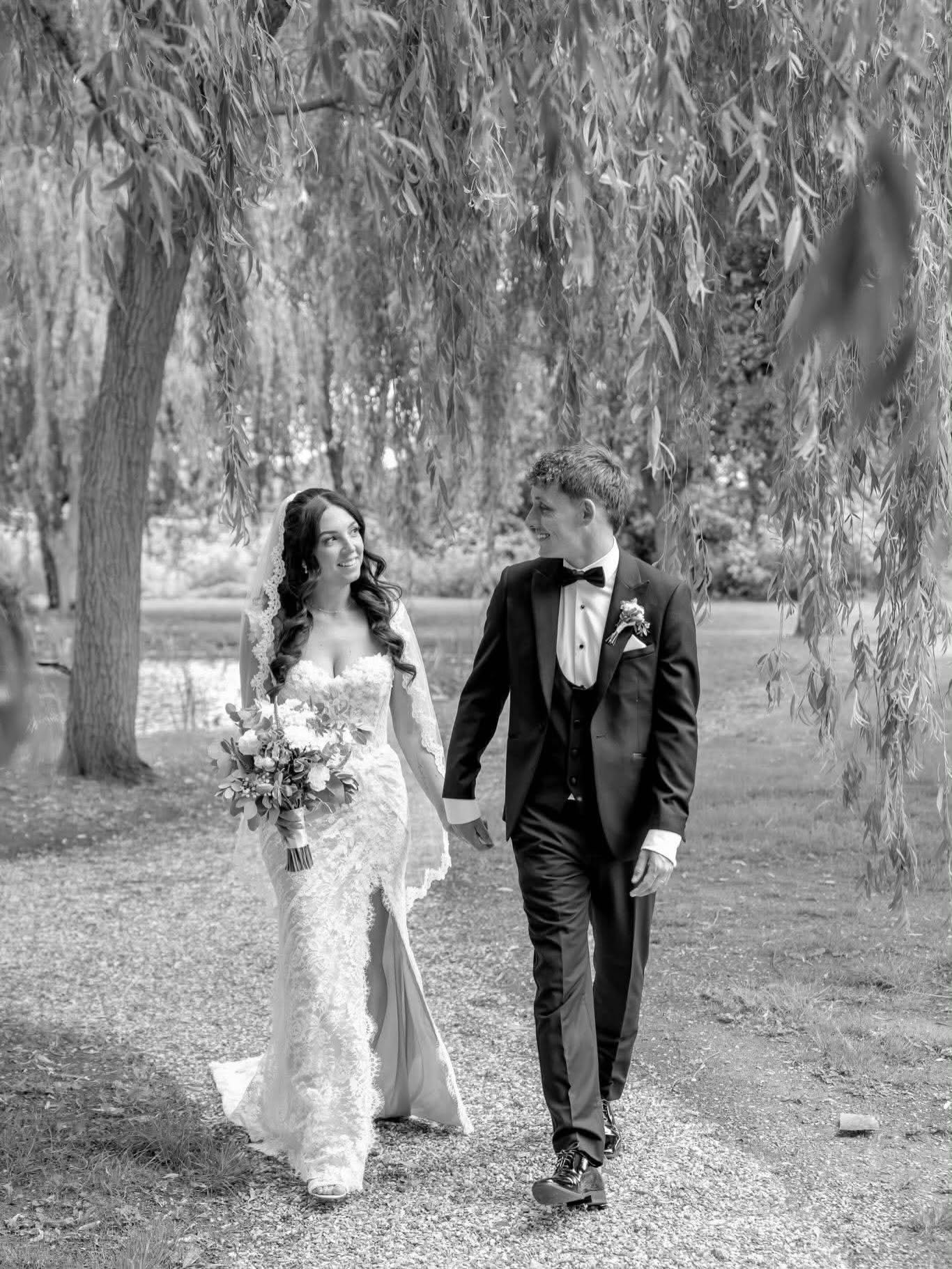 Bride & Groom with bouquet walking amongst the trees